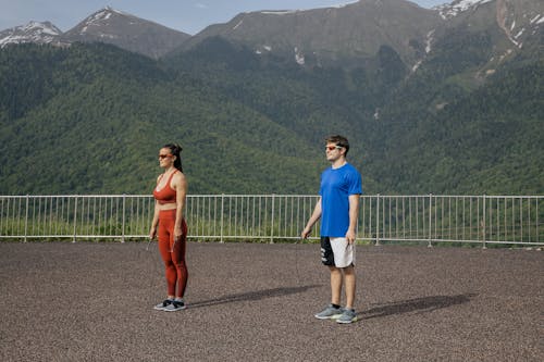 Woman and Man with Skipping Ropes Training in Mountains