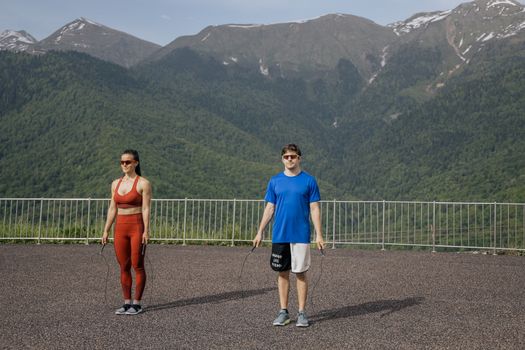 两名成年人在山脉背景下跳绳，展现了健身与自然的结合