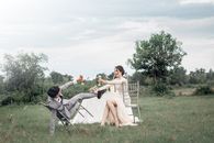 Man and Woman Sitting on White Folding Chairs on Green Grass Field