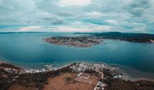 Drone view of peninsula with town in bay located between mainland and land with mountain