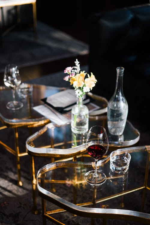 Wineglasses of fragrant red wine and sweet white wine placed on creative glass coffee table in modern lounge