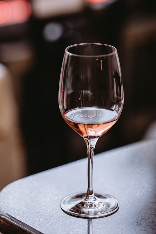 Wineglass with delicious aromatic rose wine placed on black table in modern bar