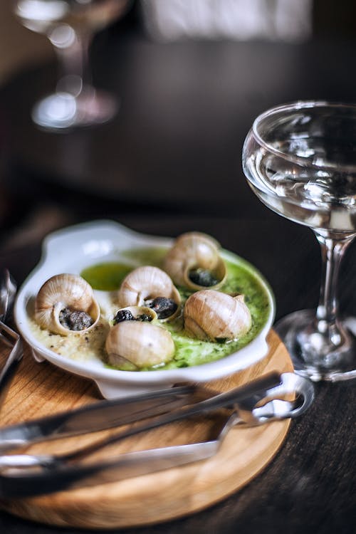 High angle delicious escargots appetizer served on wooden board in fine dining French restaurant