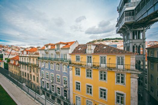 Exterior of bright old residential houses located near calm canal and reflecting on water surface against cloudy sky on street in city
