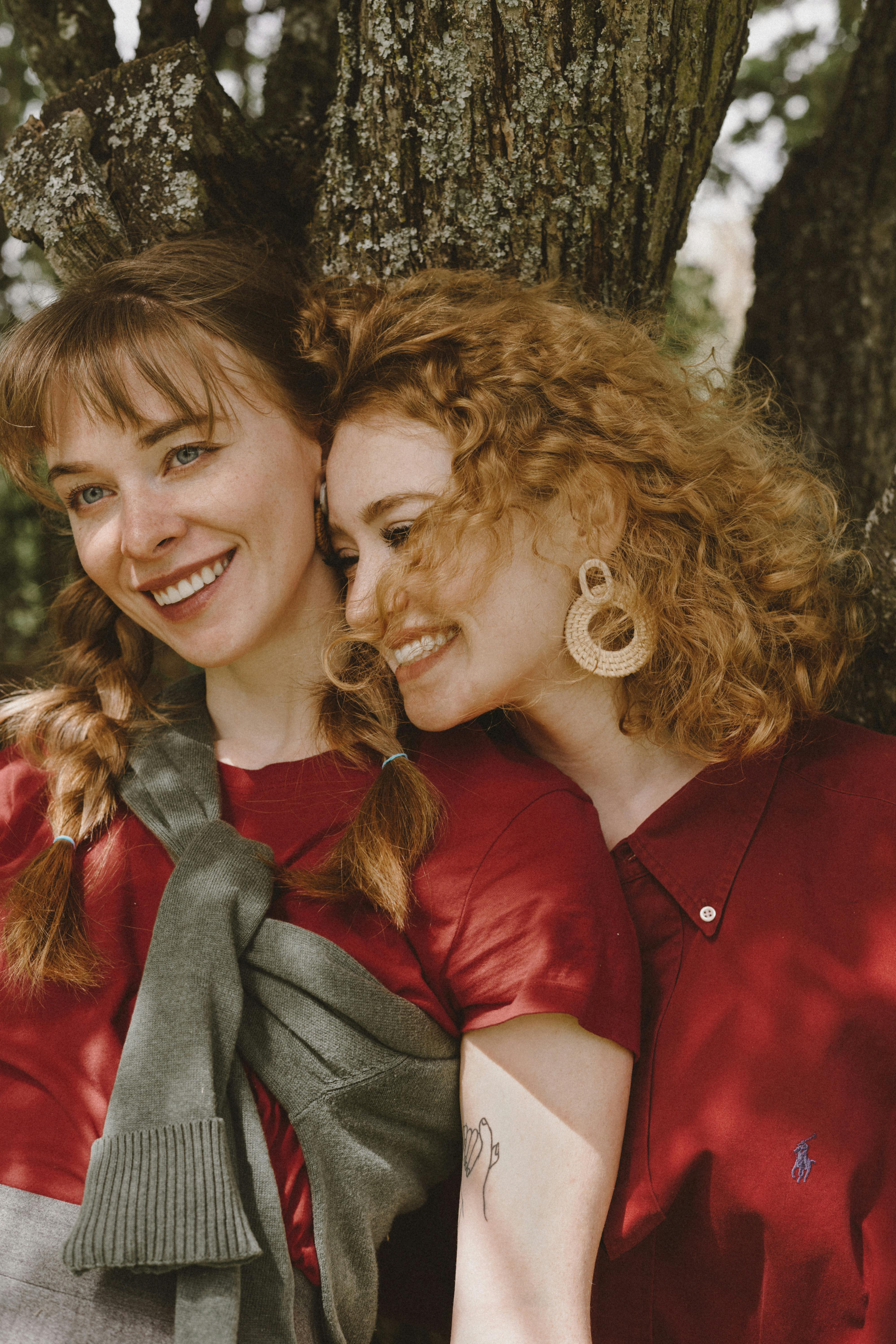 positive homosexual couple cuddling near tree