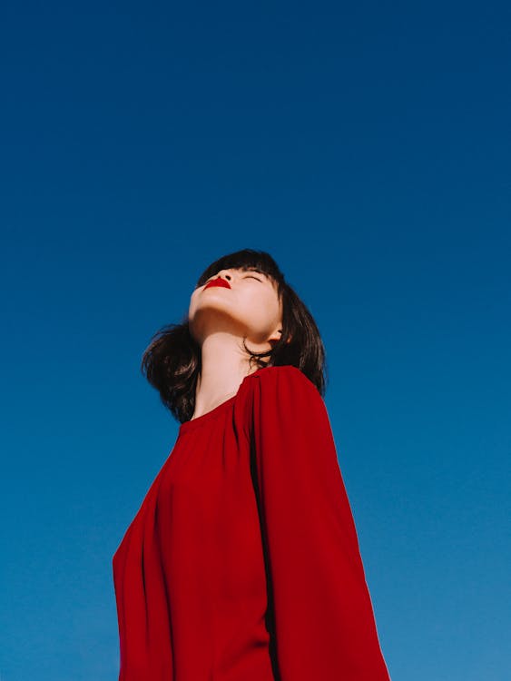 Free Stylish Asian woman with bright red lips enjoying sunny weather Stock Photo