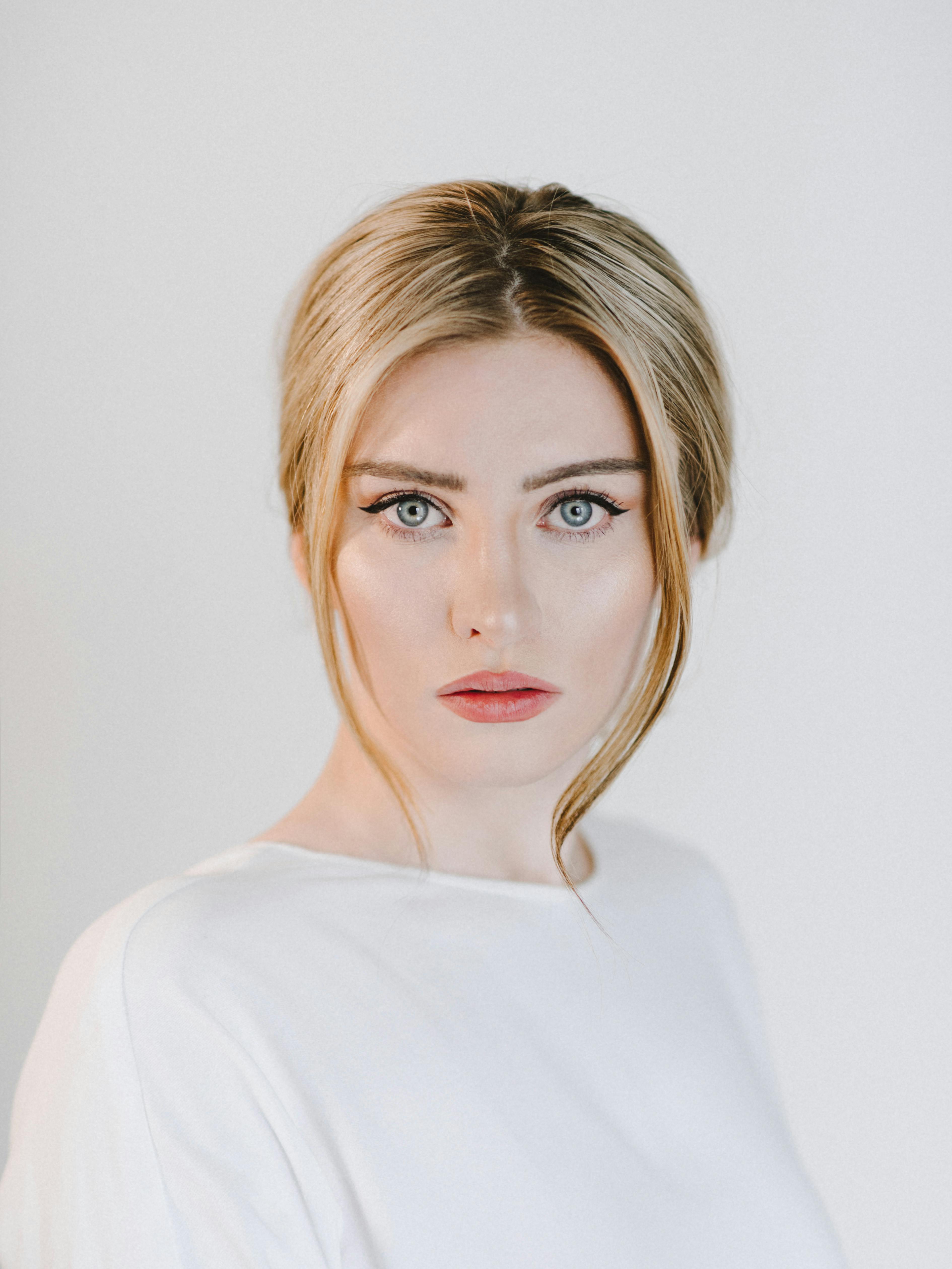 Free Young content tender female with eyeliner looking at camera on white background of studio Stock Photo