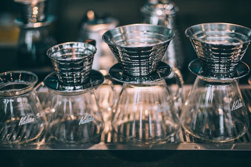 Set of similar crystal glass coffee pots with funnels for filters in coffee shop