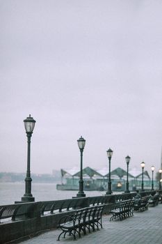 河畔长廊宁静，复古路灯与长凳映衬着阴沉的天空