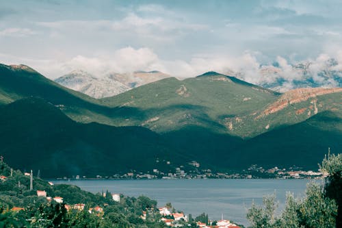 Breathtaking view of calm lake among green hills and village in mountainous area