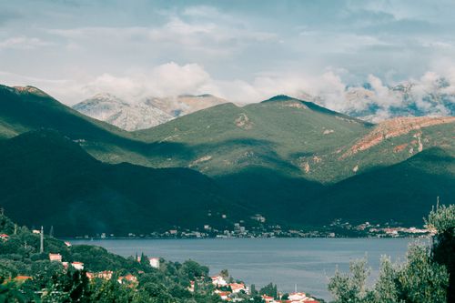 Free Breathtaking view of calm lake among green hills and village in mountainous area Stock Photo