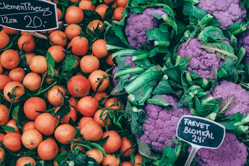Free From above of fresh ripe colorful citrus fruits placed near violet healthy cauliflower on market Stock Photo