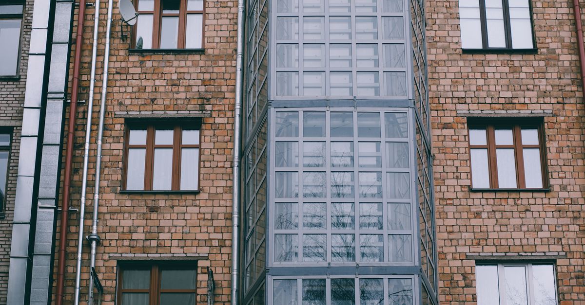 Low angle of facade of brick apartment building with windows and glass corner