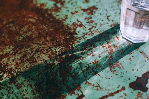 Glass goblet on rusty corroded metal surface