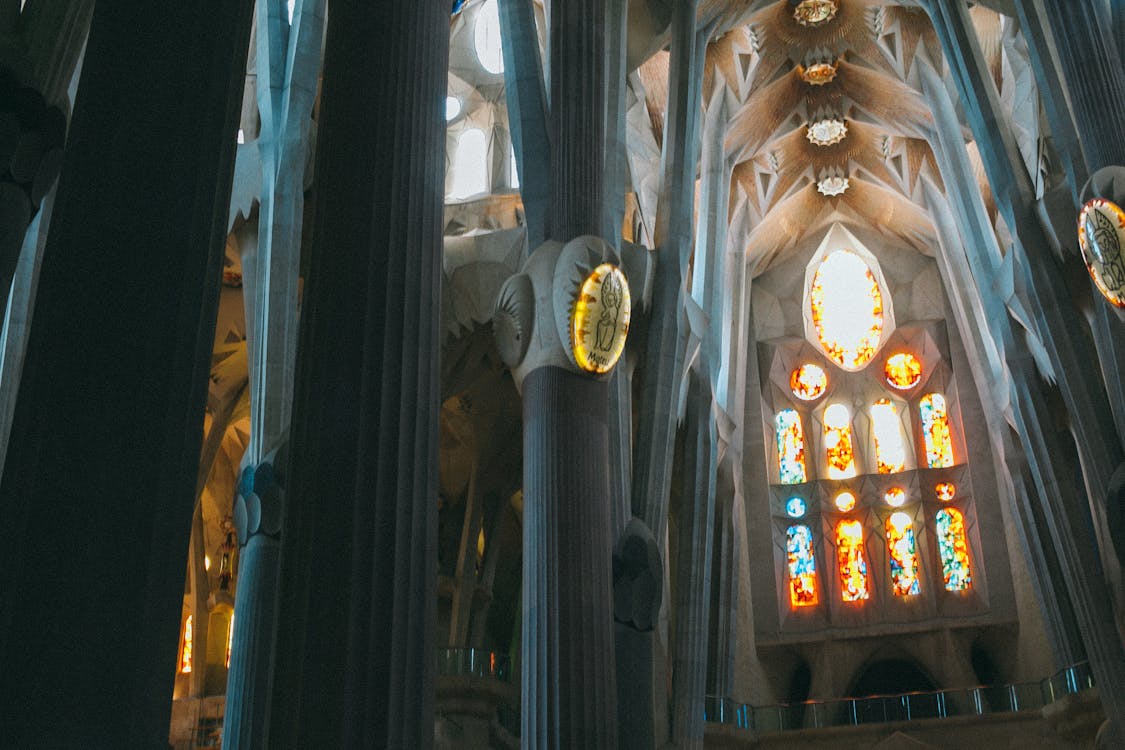 From below of tall columns and ceiling in Gothic style in Catholic landmark of Spain Sagrada Familia