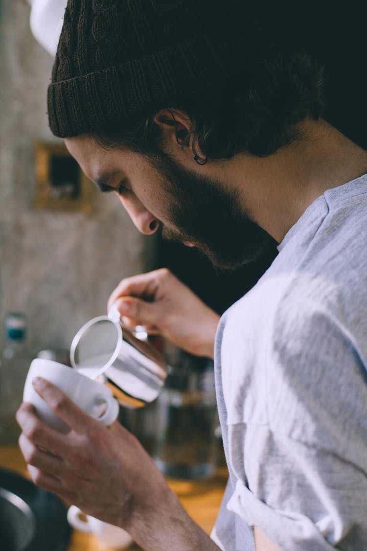 Faceless Man Pouring Milk In Coffee In Cafe