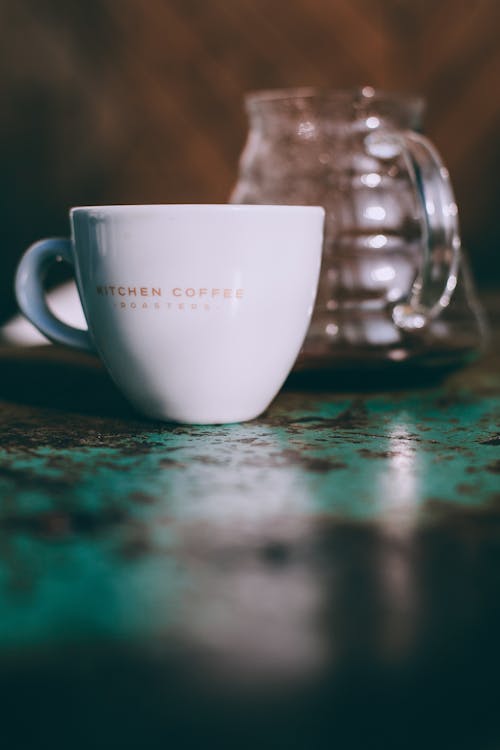 Free White ceramic cup with coffee near glass utensil placed on shabby surface in cafe Stock Photo