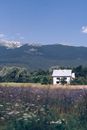 Small house located near grassy field and mountains