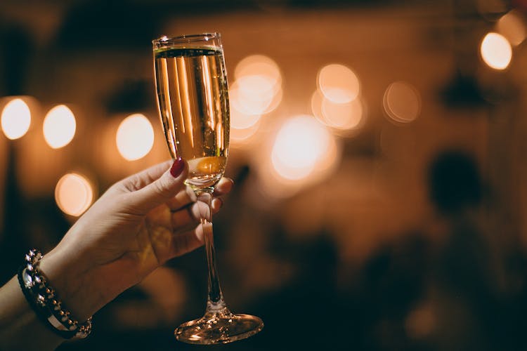 Unrecognizable Woman With Glass Of Champagne In Restaurant