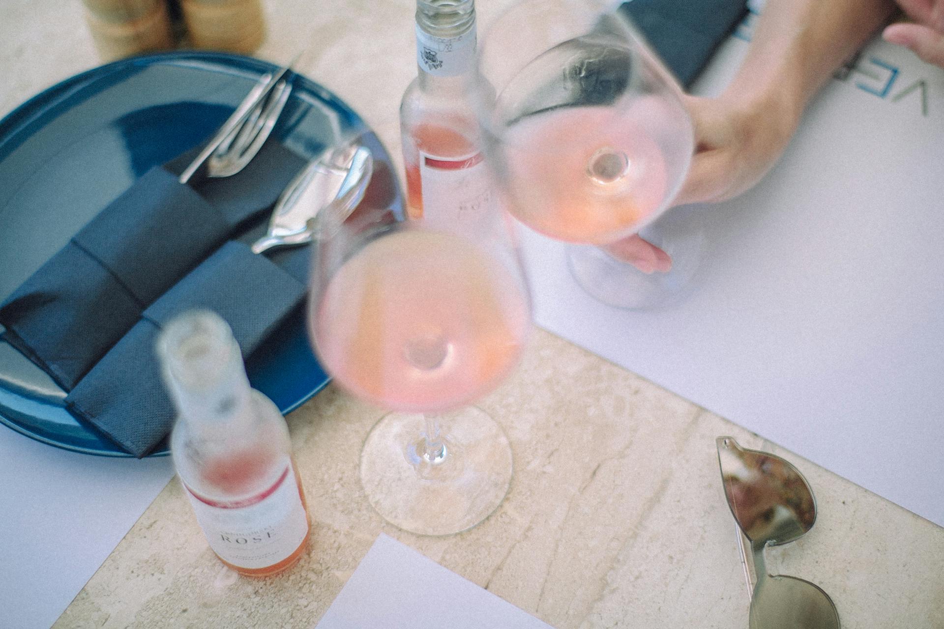 From above of crop anonymous female with glass of rose wine having date with partner