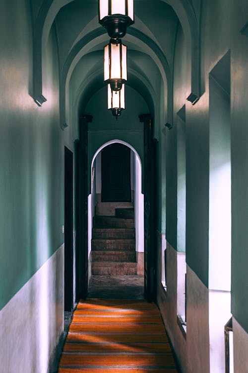 Interior of empty narrow passage with lamps and arched entrance leading to stairs