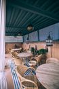 Interior design of summer terrace of cozy cafe with wooden round tables and wicker chairs