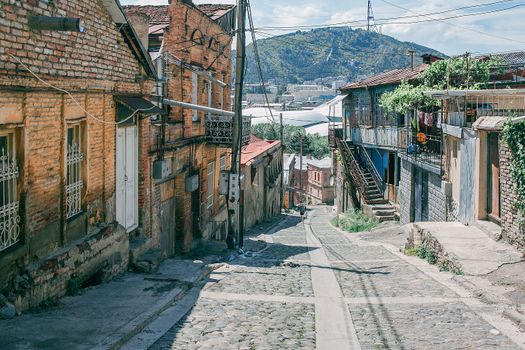 Charming old town street with view of hills. Historic, rustic architecture outdoors.