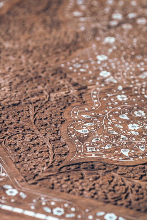 From above closeup of brown wooden table surface with carved ornamental elements and decorative details