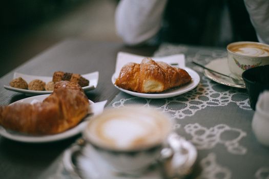 Crop person with coffee and croissant