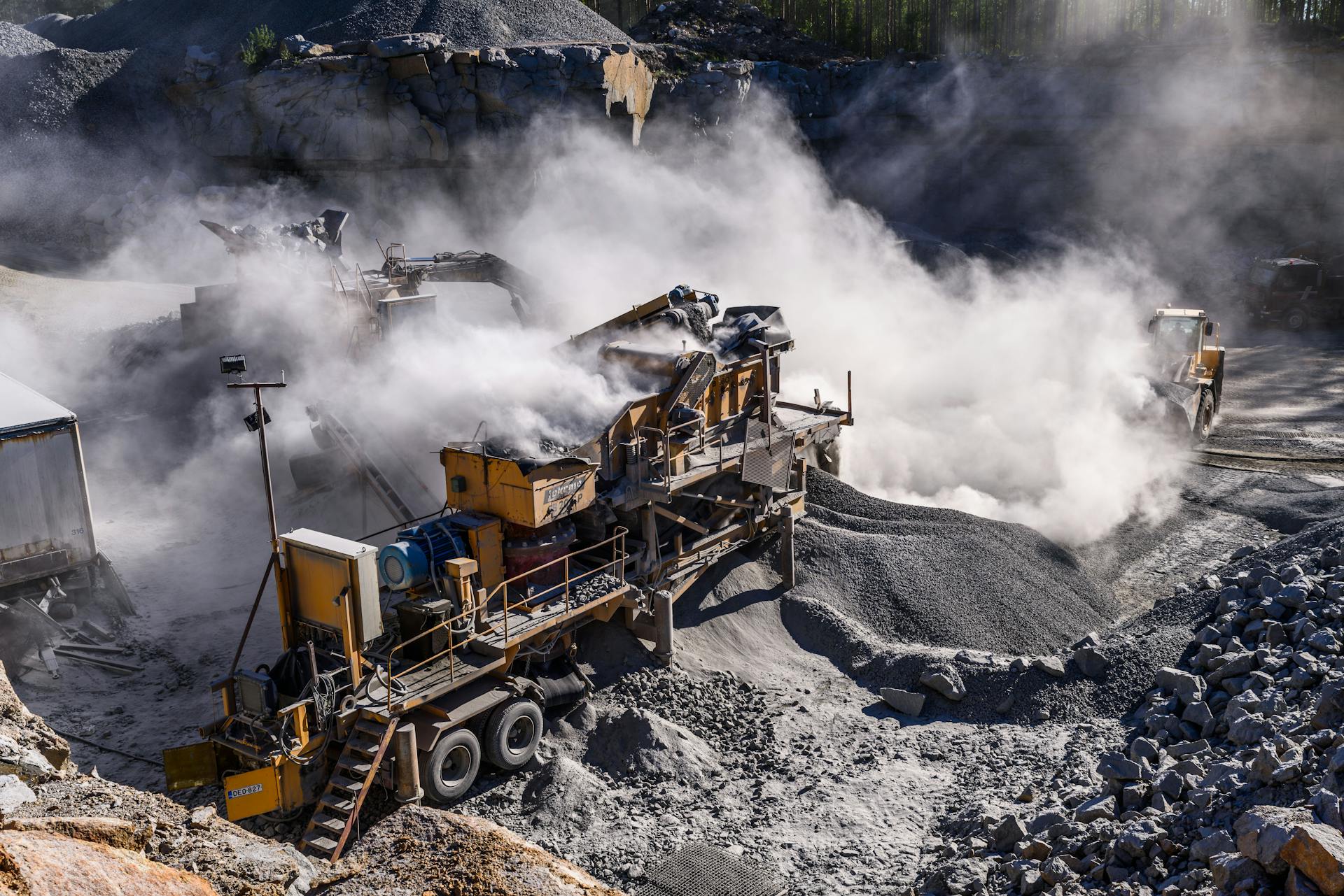 A dynamic industrial quarry scene in Honkajoki, Finland, showcasing heavy machinery and dust clouds.