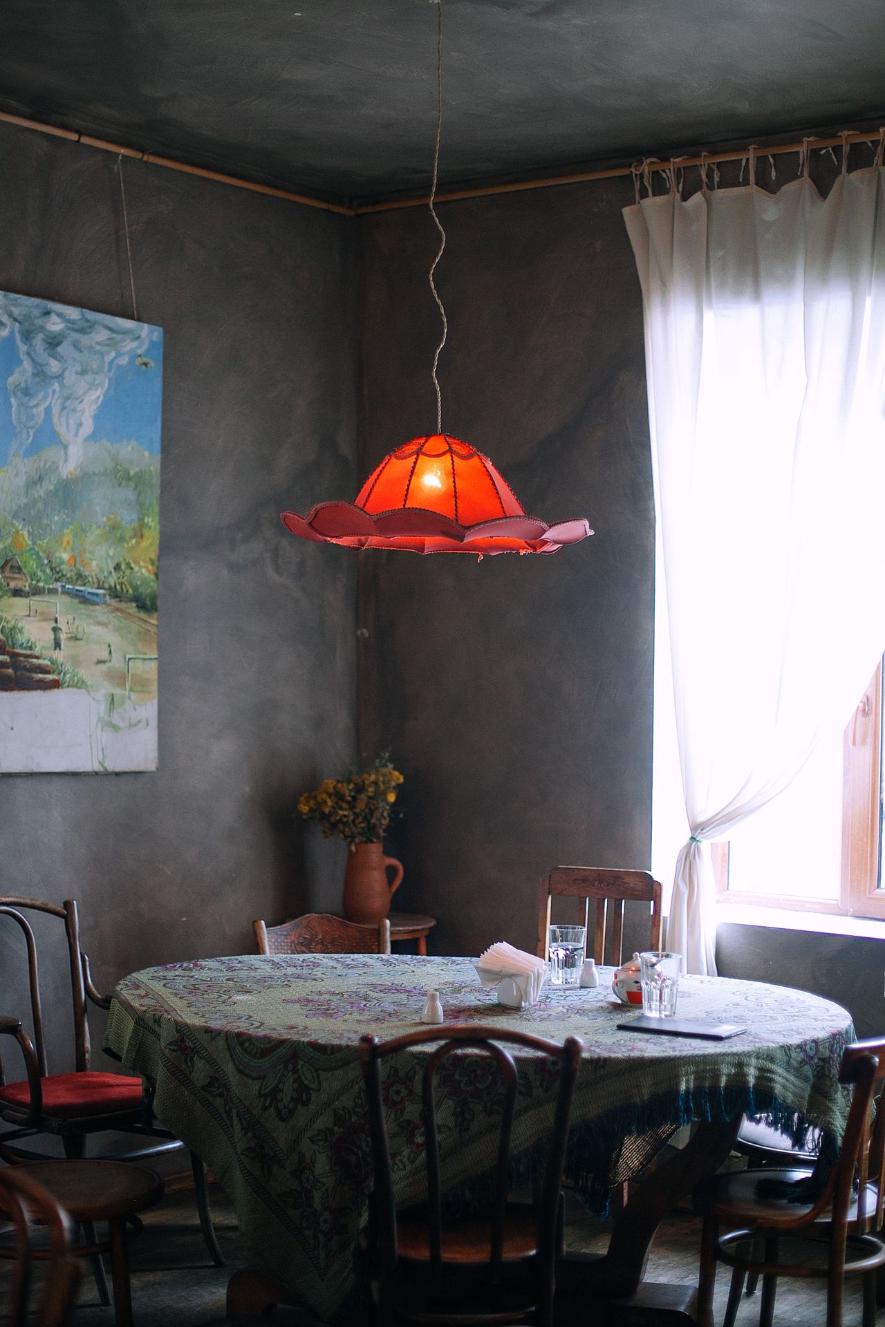 Dining room with gray walls, round table, and red pendant light