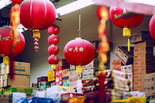 Colorful Chinese lanterns hanging amidst carton boxes with food in storage on market