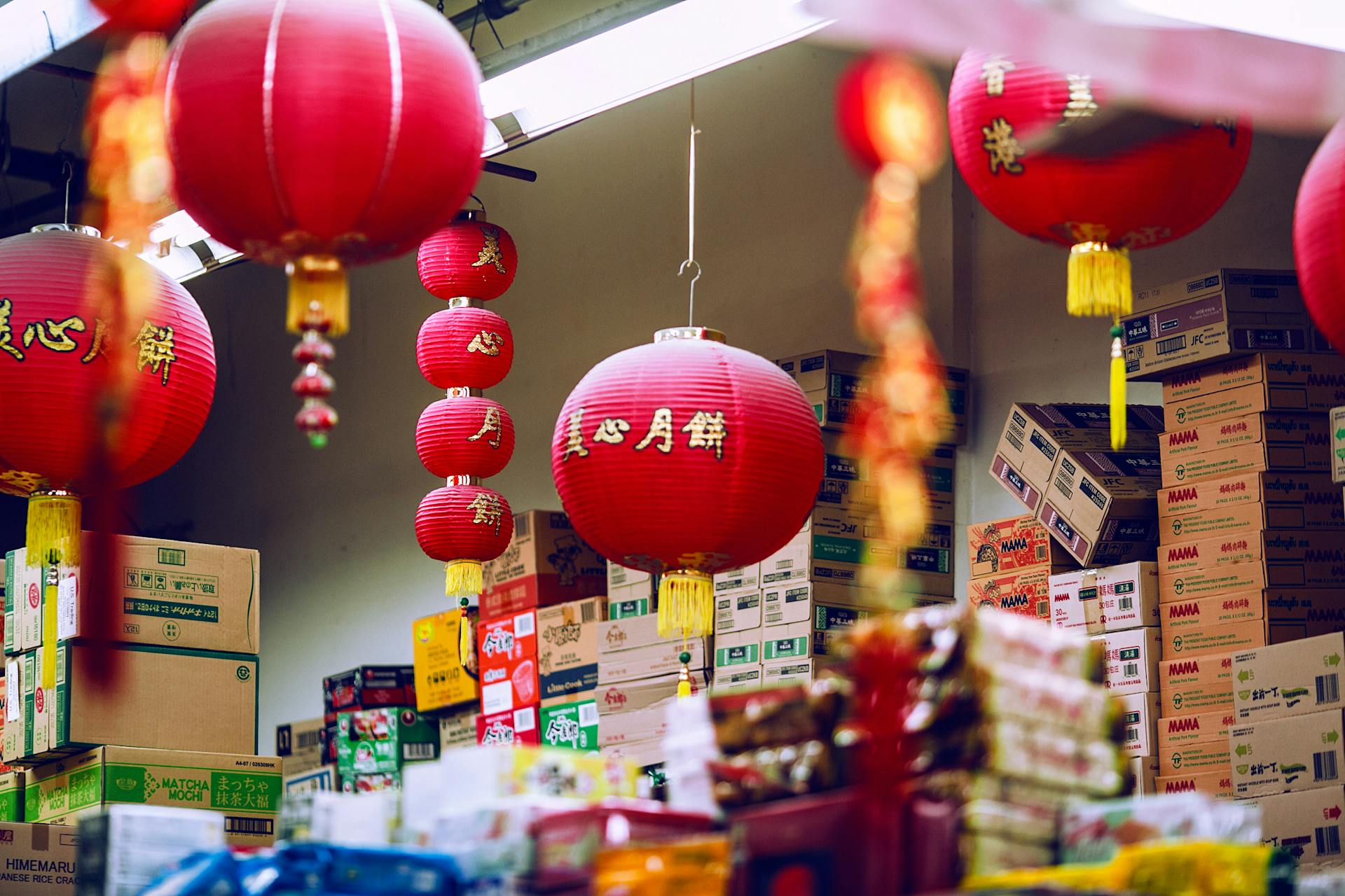 Colorful Chinese lanterns hanging amidst carton boxes with food in storage on market