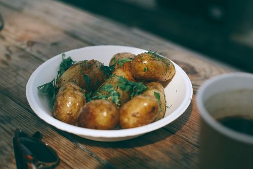 Free From above of tasty appetizing roasted potatoes with greenery in white plate on wooden table Stock Photo