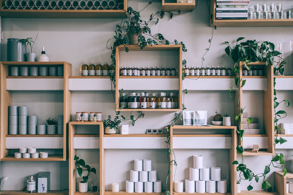 Free Creative interior design of small shop with wooden shelves full of assorted colorful bottles and green plants Stock Photo