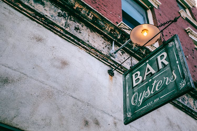 Signboard With Bar Inscription On Old Building Wall In Town