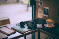 Headphones near smartphone and cappuccino on cafe table