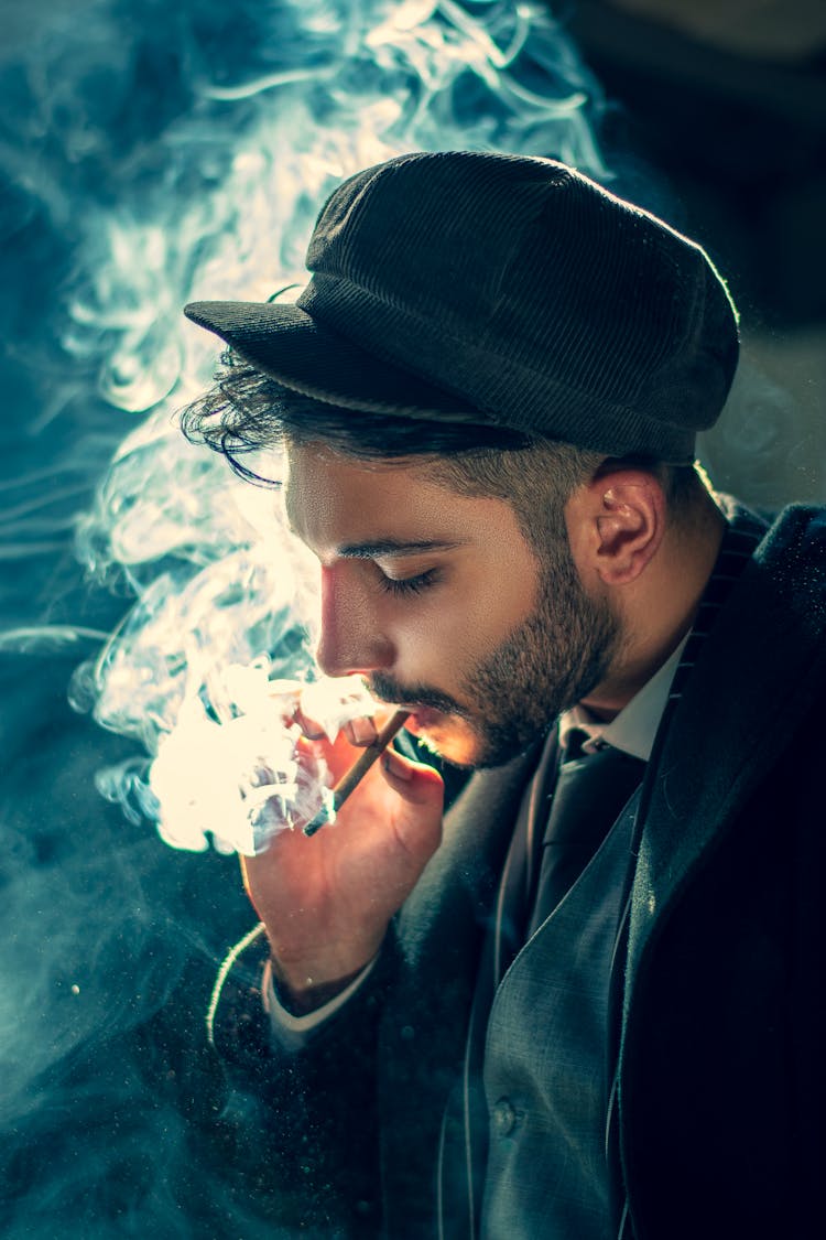 A Man Smoking Cigarette Wearing A Black Hat