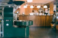 Coffee roasting machine in cafe with anonymous barista and girlfriend