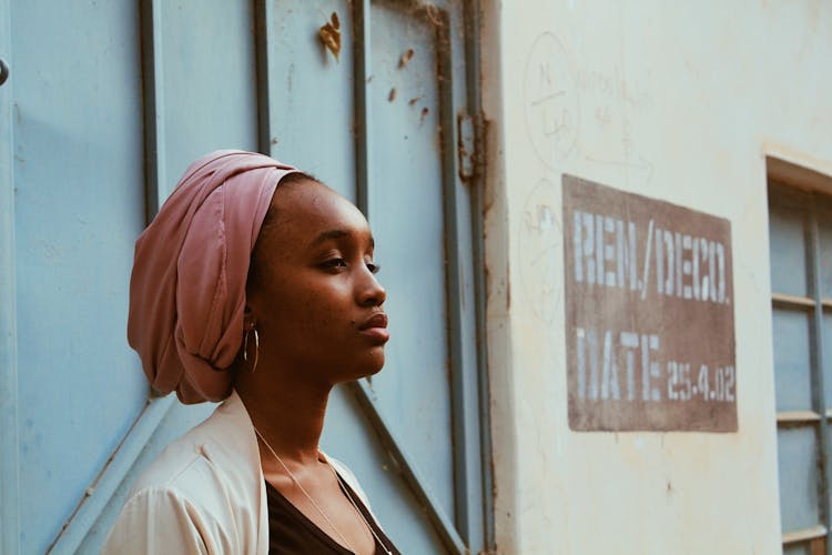 Black Woman In Headscarf Next To Old Massive Door