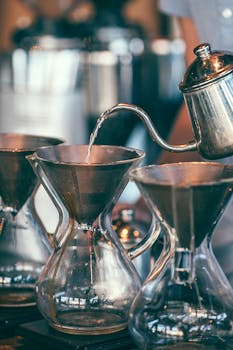 Drip coffee brewing in a café setting with elegant glass Chemex carafes.