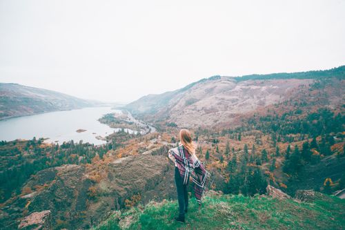 Free Back view of anonymous traveler in ornamental shawl enjoying river between mounts under light sky Stock Photo