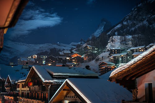 無料 夜の間に雪に覆われた山の近くの木造家屋 写真素材