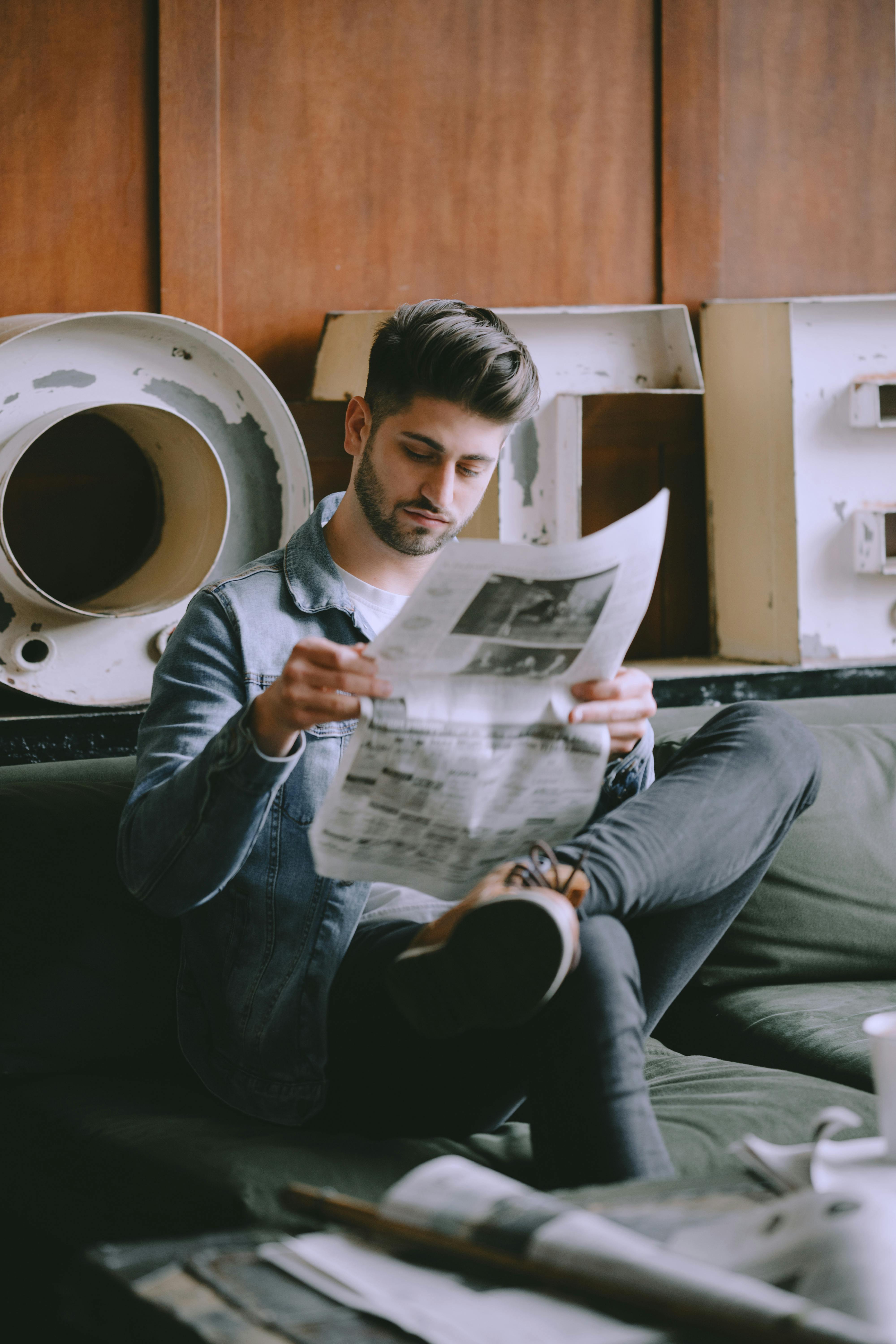 focused man with newspaper in light room