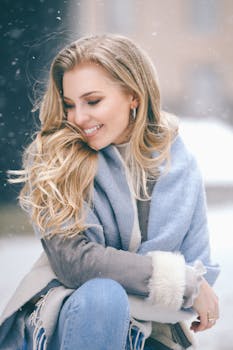Cheerful woman with blond hair wearing winter clothes, smiling in the snow.