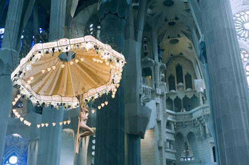 From below pillars and decorative ceiling with ornamental chandelier in Basilica de la Sagrada Familia in Barcelona