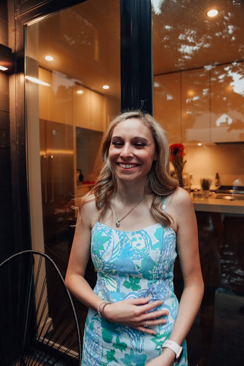 Positive young woman smiling by transparent wall of luxury house