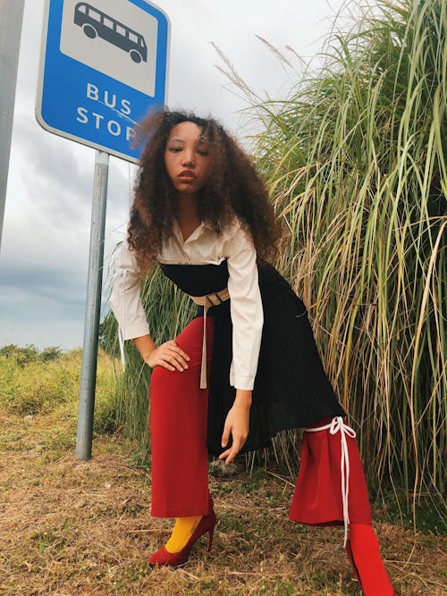 Stylish ethnic woman standing near road sign