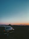Parked car under colorful sky at sunset