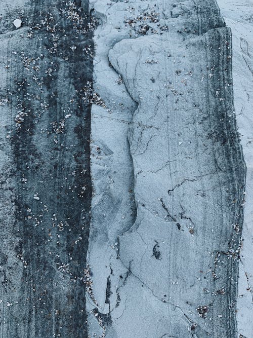 Top view of abstract background of dry uneven rocky surface in blue and white color